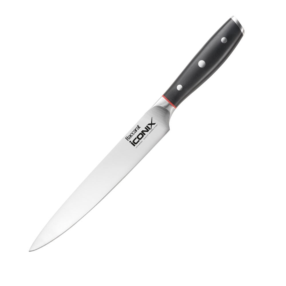 Sliced meat on a wooden board garnished with herbs next to a Baccarat Iconix Carving Knife 20cm
