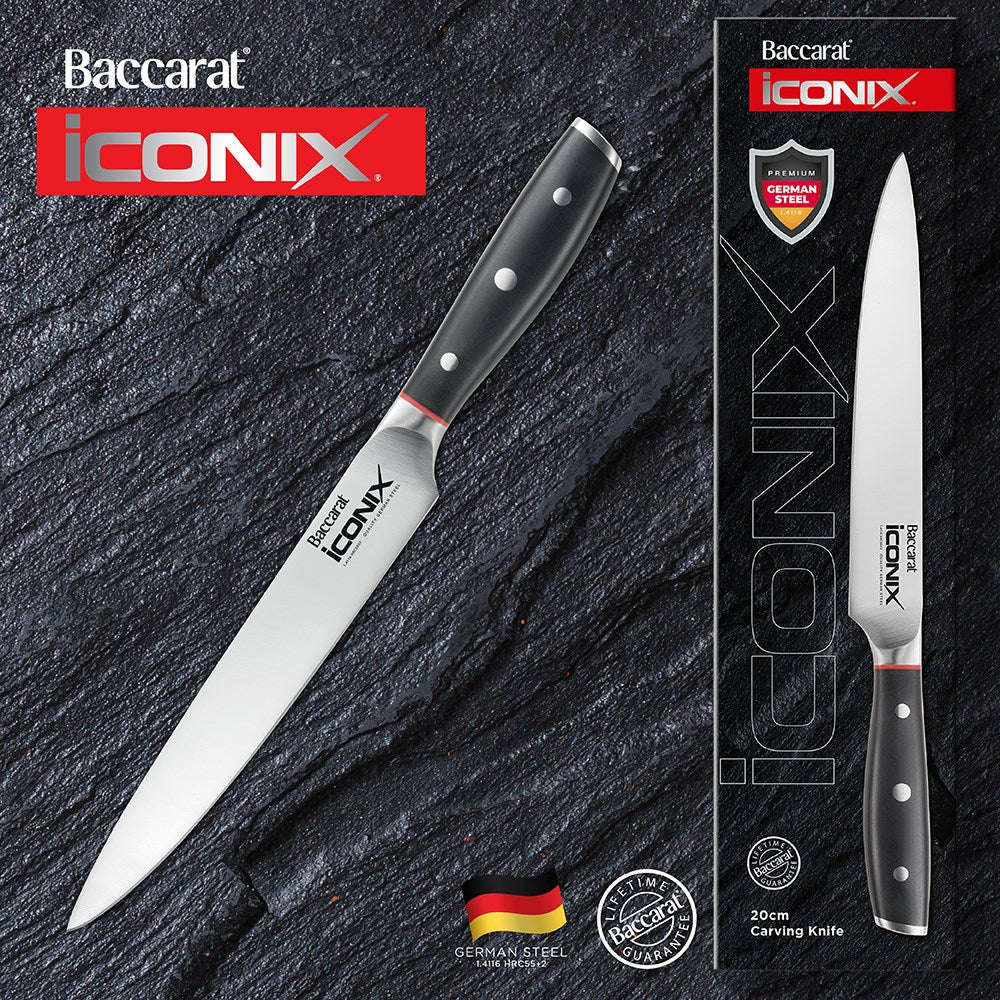 Sliced meat on a wooden board garnished with herbs next to a Baccarat Iconix Carving Knife 20cm