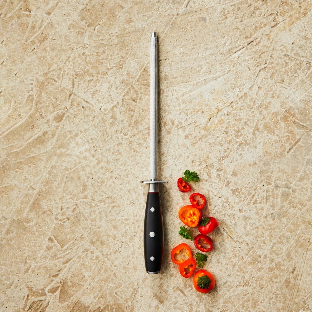 Knife sharpener on beige surface with sliced red and green peppers- Baccarat Iconix Sharpening Steel