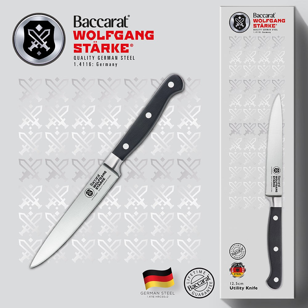 A black-handled knife on a wooden cutting board with sliced strawberries - Baccarat Wolfgang Starke