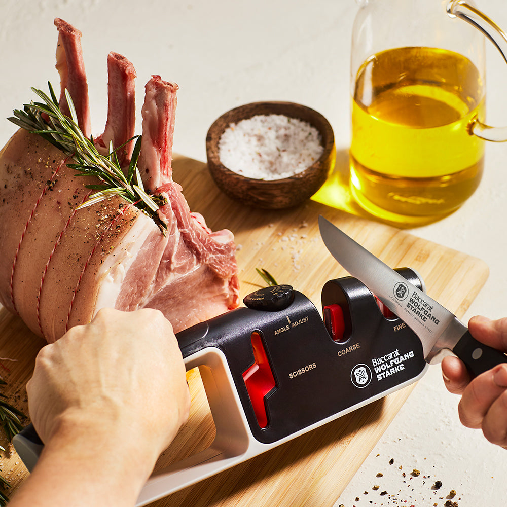 Person sharpening a knife with a black and red santoku knife 18cm - Baccarat wolfgang starke