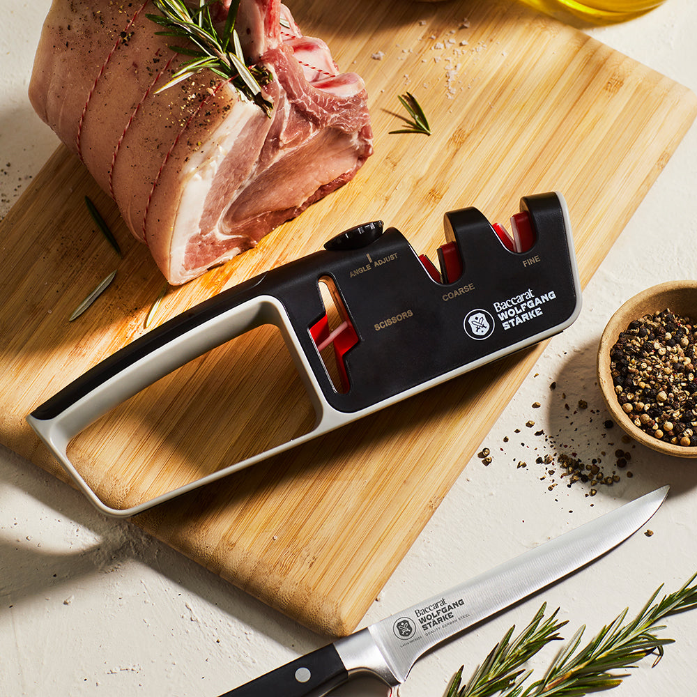 Person sharpening a knife with a black and red santoku knife 18cm - Baccarat wolfgang starke