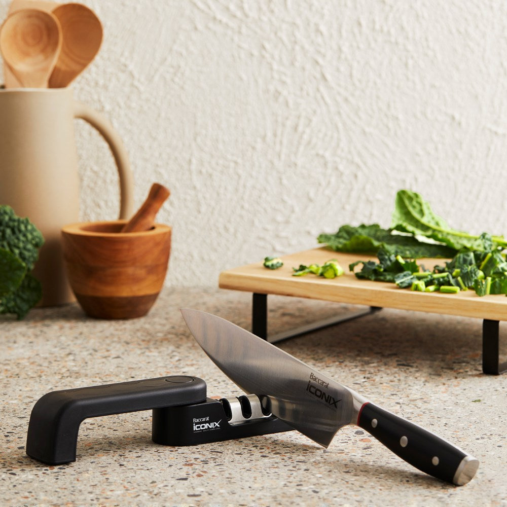A kitchen counter with herbs wooden utensils and a black knife sharpener - Baccarat wolfgang starke