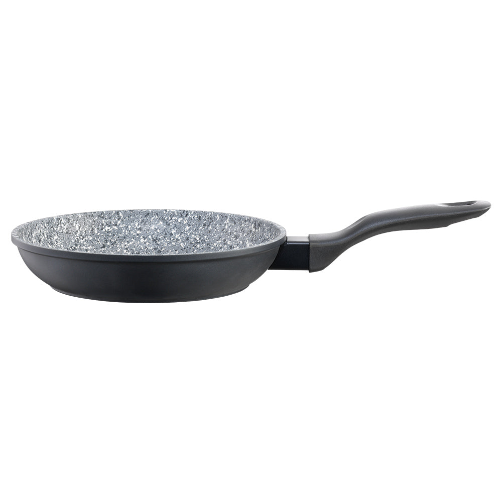Frying pan with green peas broccoli and onions on a black surface beside a beige cloth - Baccarat