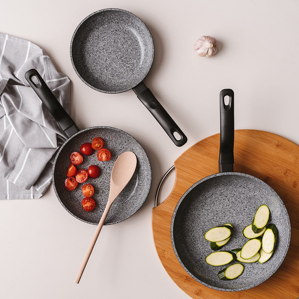 Baccarat stonex2 Ceramic non-stick frying pans of varying sizes with vegetables and a wooden spoon