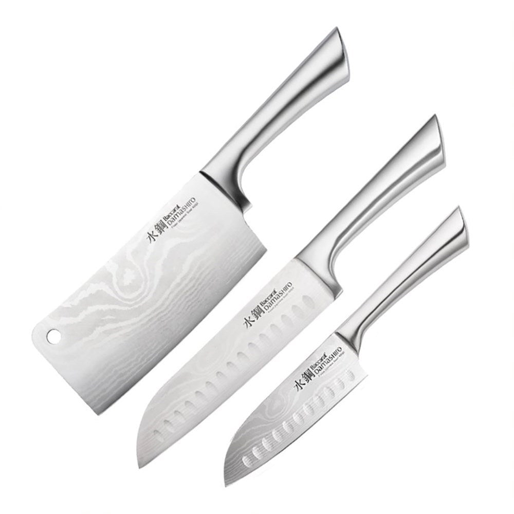 Three stainless steel knives next to whole and sliced limes grey surface - Baccarat Damashiro
