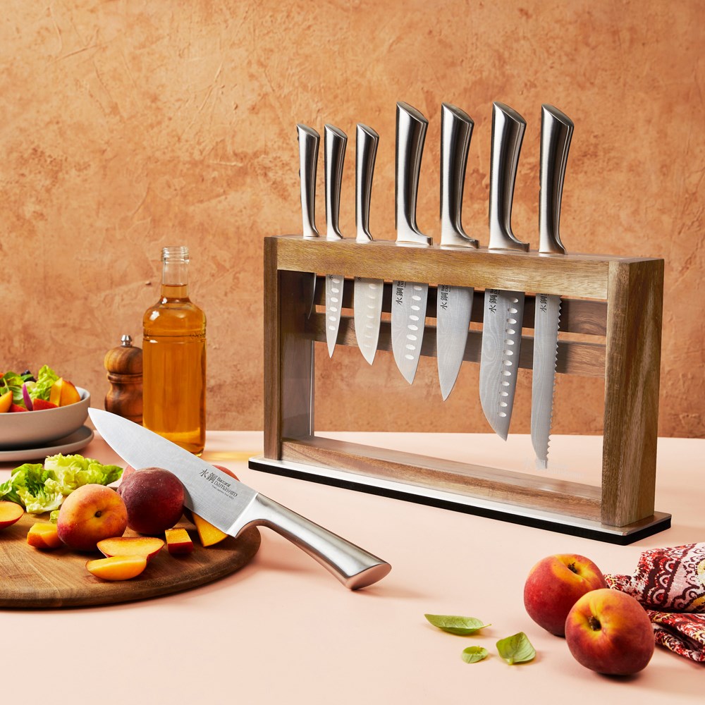 Slices of peaches on a wooden board next to a salad bowl and knives in the background - Baccarat