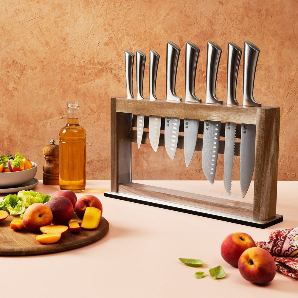 Slices of peaches on a wooden board next to a salad bowl and knives in the background - Baccarat