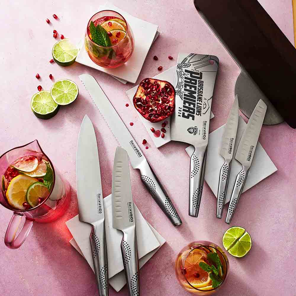 Sharp stainless steel kitchen knives with lime slices and cocktails on a pink surface - Baccarat