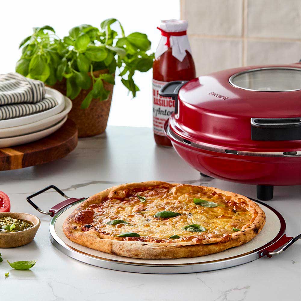 Red gourmet slice pizza oven with temperature dial beside a plant and tomato sauce bottle - Baccarat