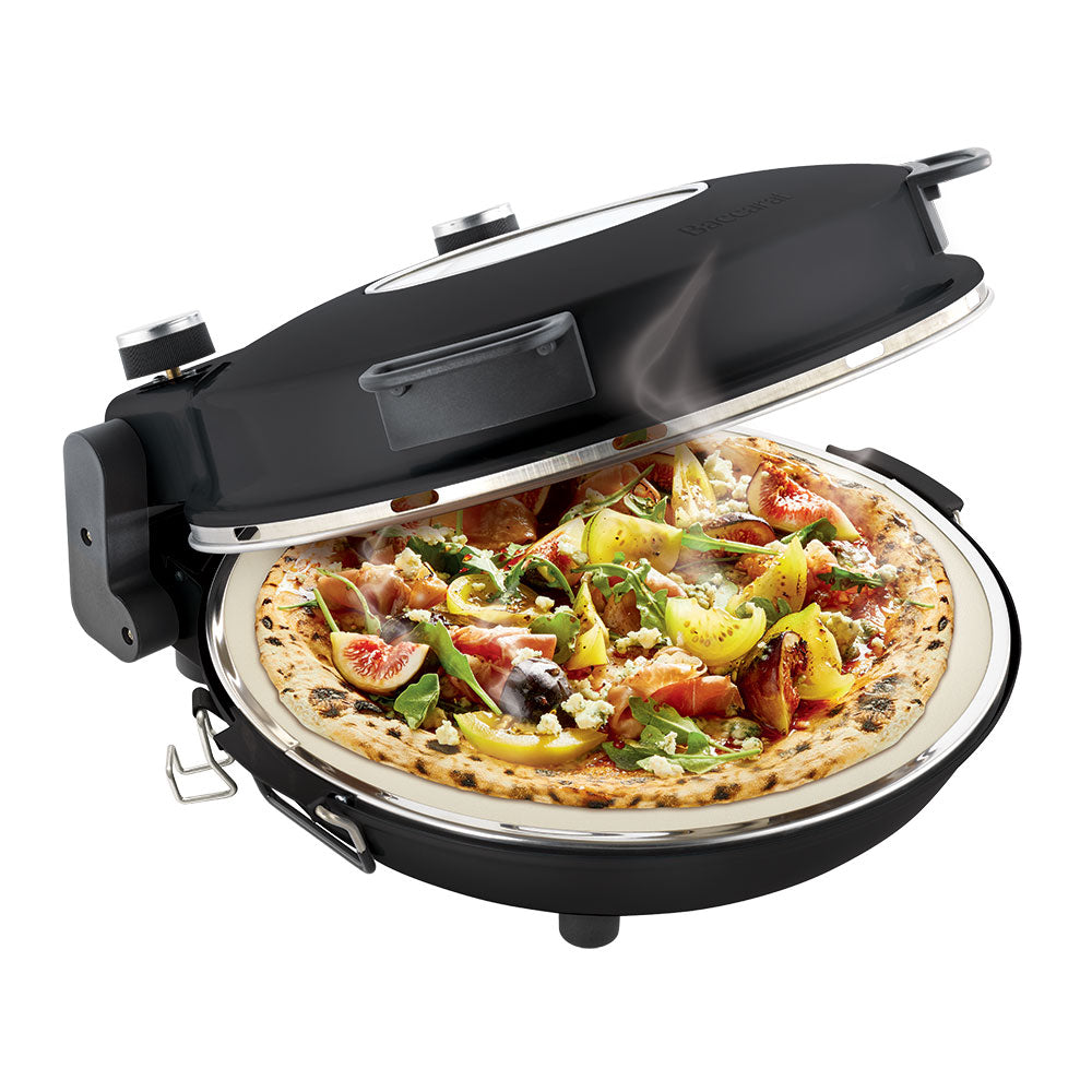 A pizza maker with a freshly cooked pizza red pizza oven surrounded by plates and drinks - Baccarat
