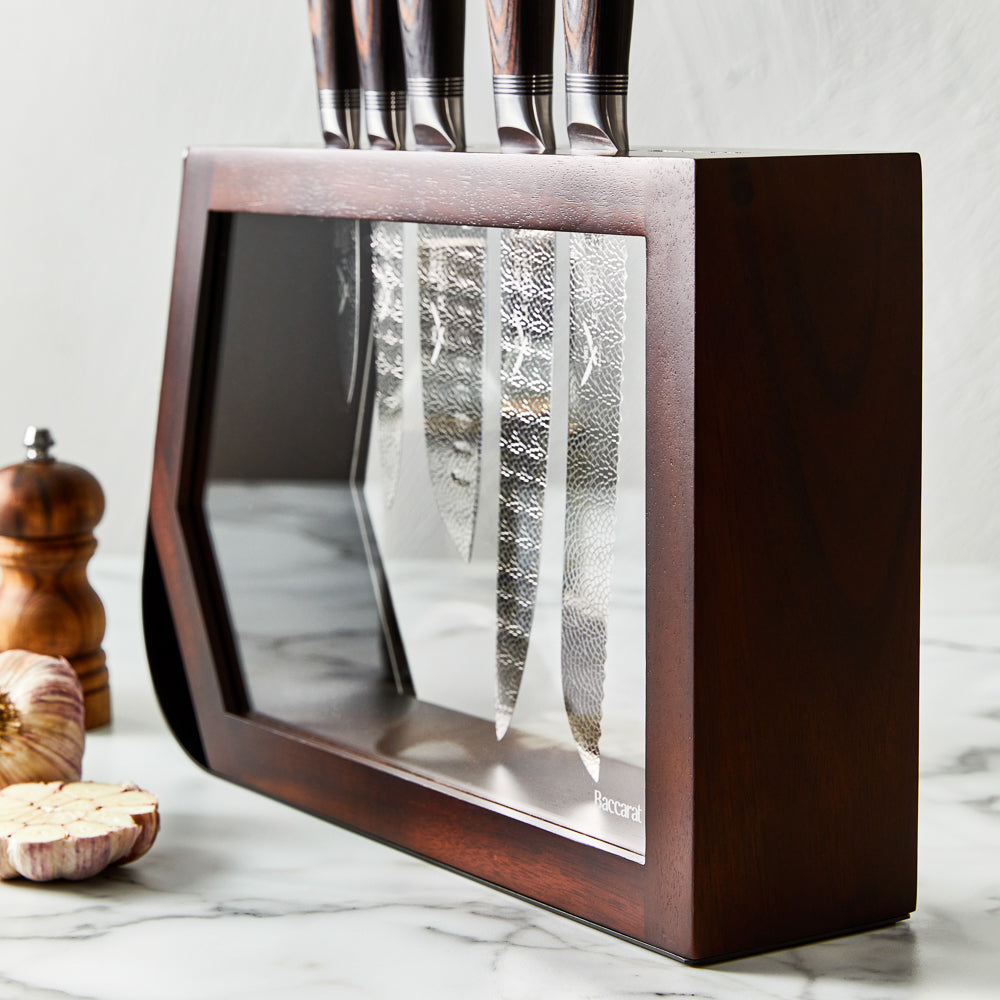Chef's knife slicing garlic on a kitchen counter shiny silver blade 7 piece knife block - Baccarat