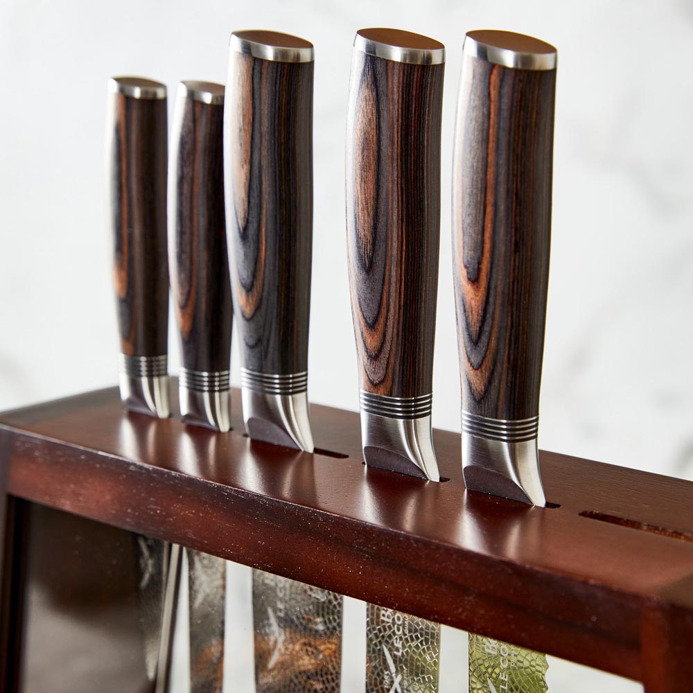 Chef's knife slicing garlic on a kitchen counter shiny silver blade 7 piece knife block - Baccarat
