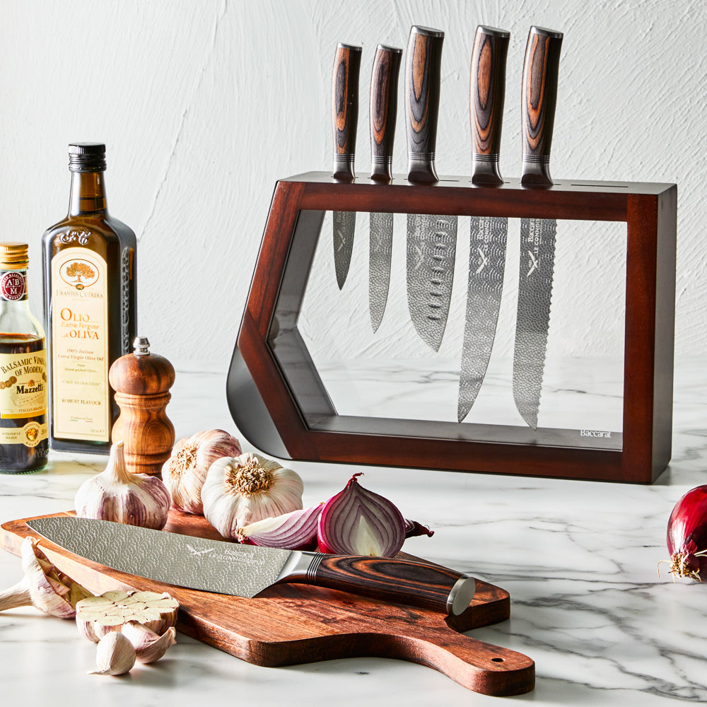 Chef's knife slicing garlic on a kitchen counter shiny silver blade 7 piece knife block - Baccarat