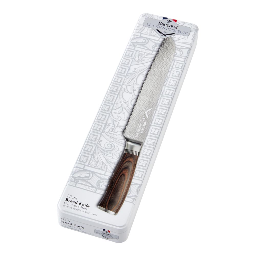 A rustic table setting with sliced bread and cheese featuring a silver bread knife 22cm - Baccarat