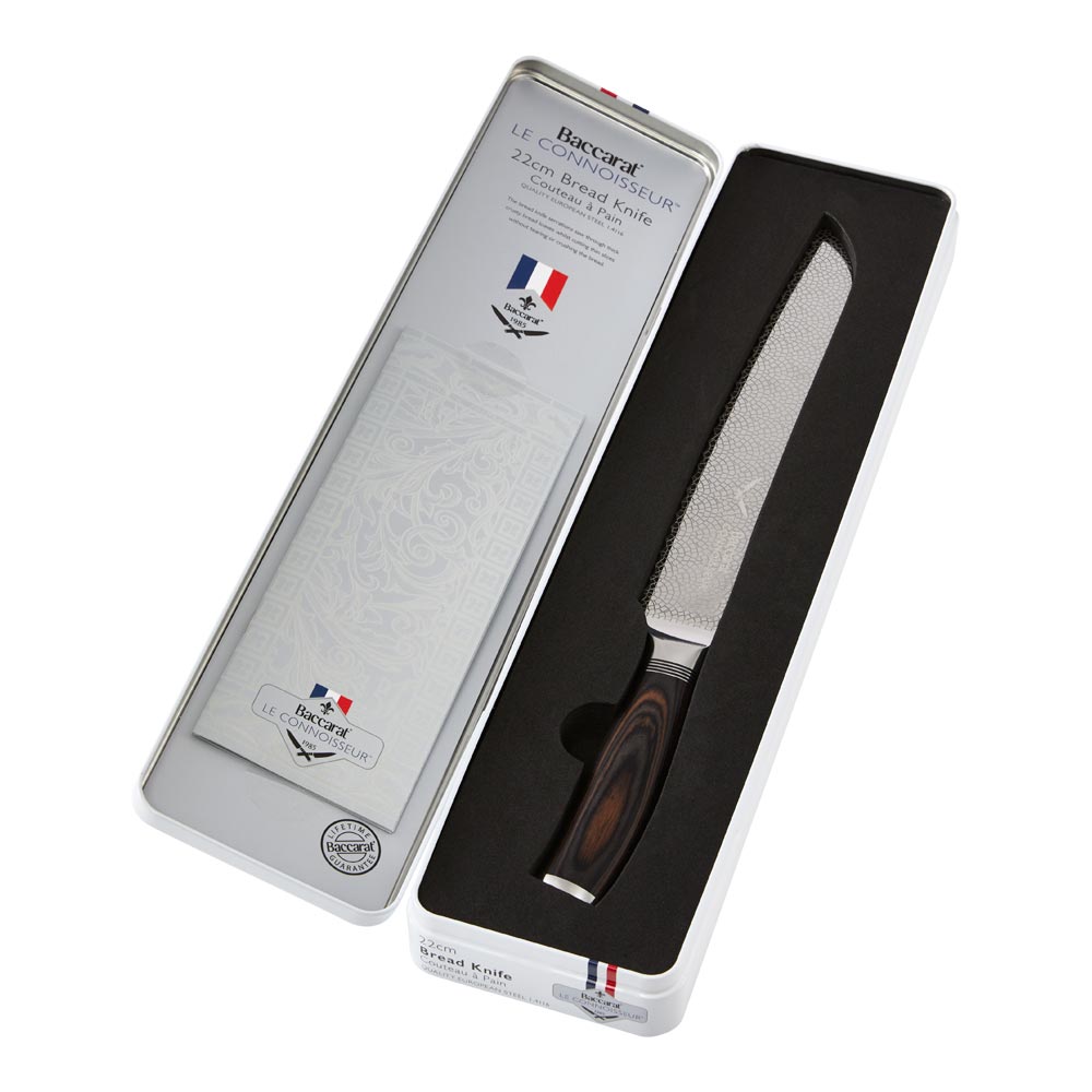 A rustic table setting with sliced bread and cheese featuring a silver bread knife 22cm - Baccarat
