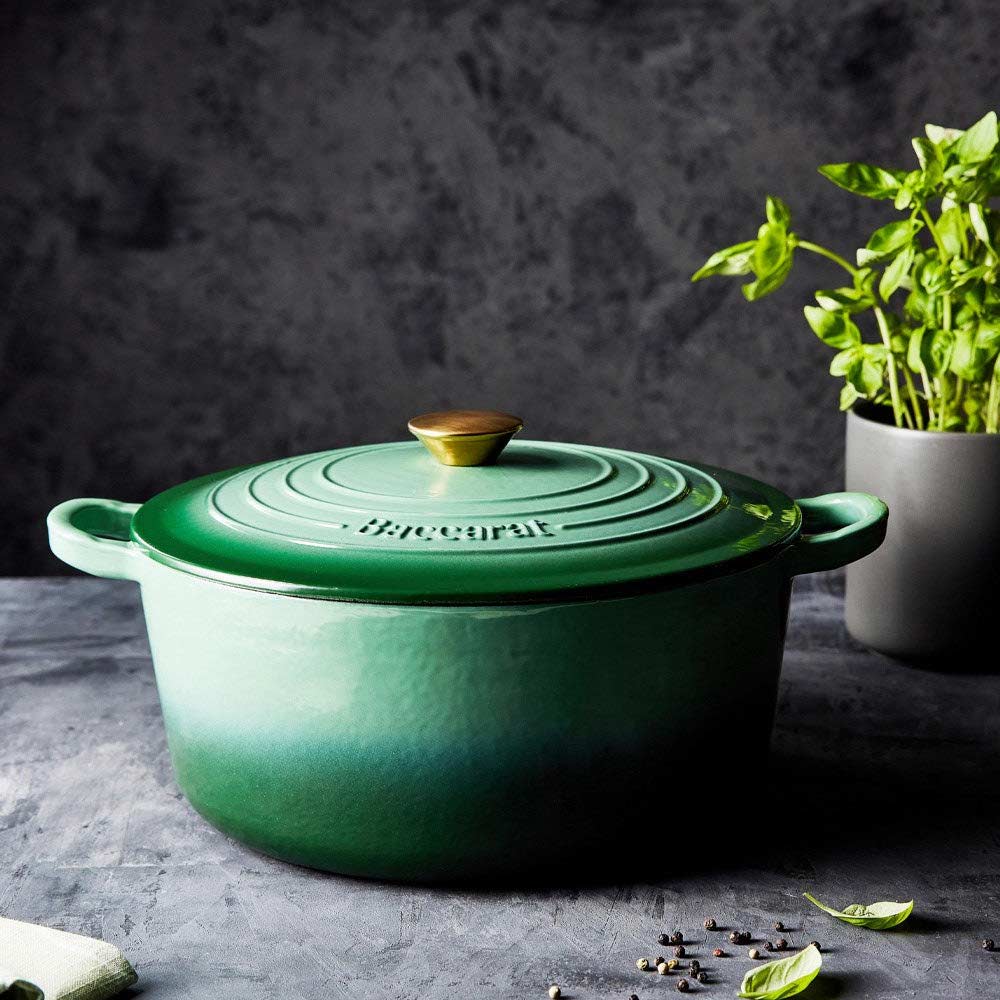 Green Baccarat Le Connoisseur French Oven with lid on countertop surrounded by herbs and a plant