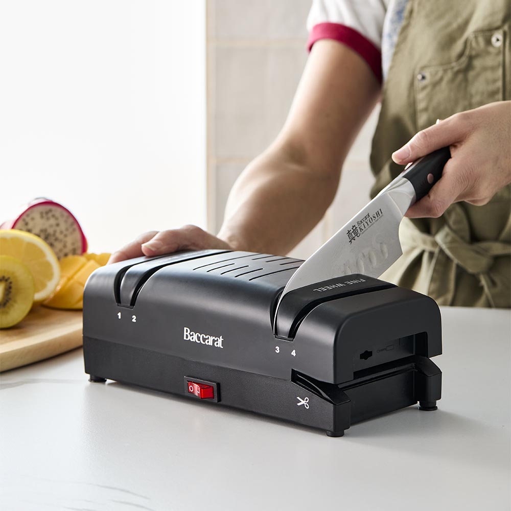 Electric knife sharpener on kitchen counter next to sliced mangoes black knife sharpener - Baccarat