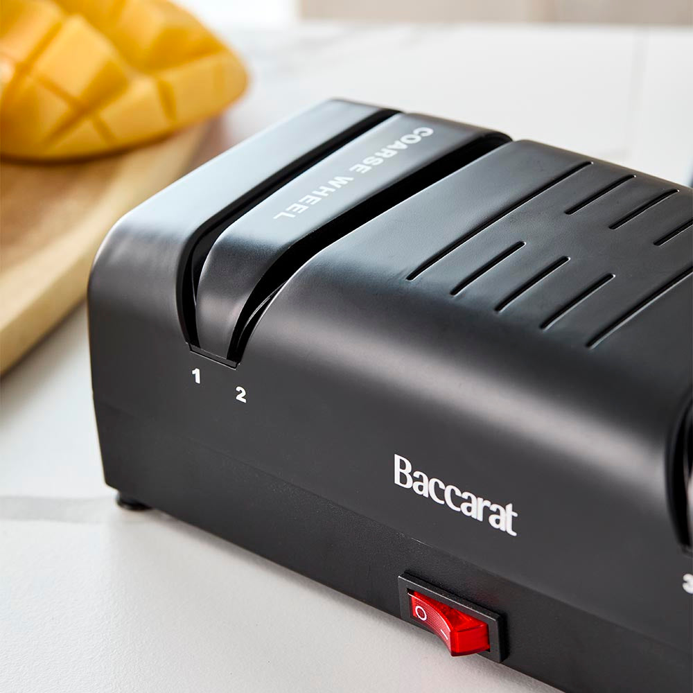 Electric knife sharpener on kitchen counter next to sliced mangoes black knife sharpener - Baccarat
