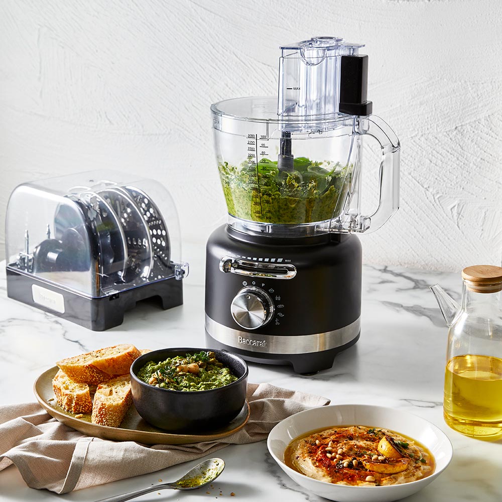 black air fryer with green ingredients on marble counter near dishes and a spice grinder - Baccarat