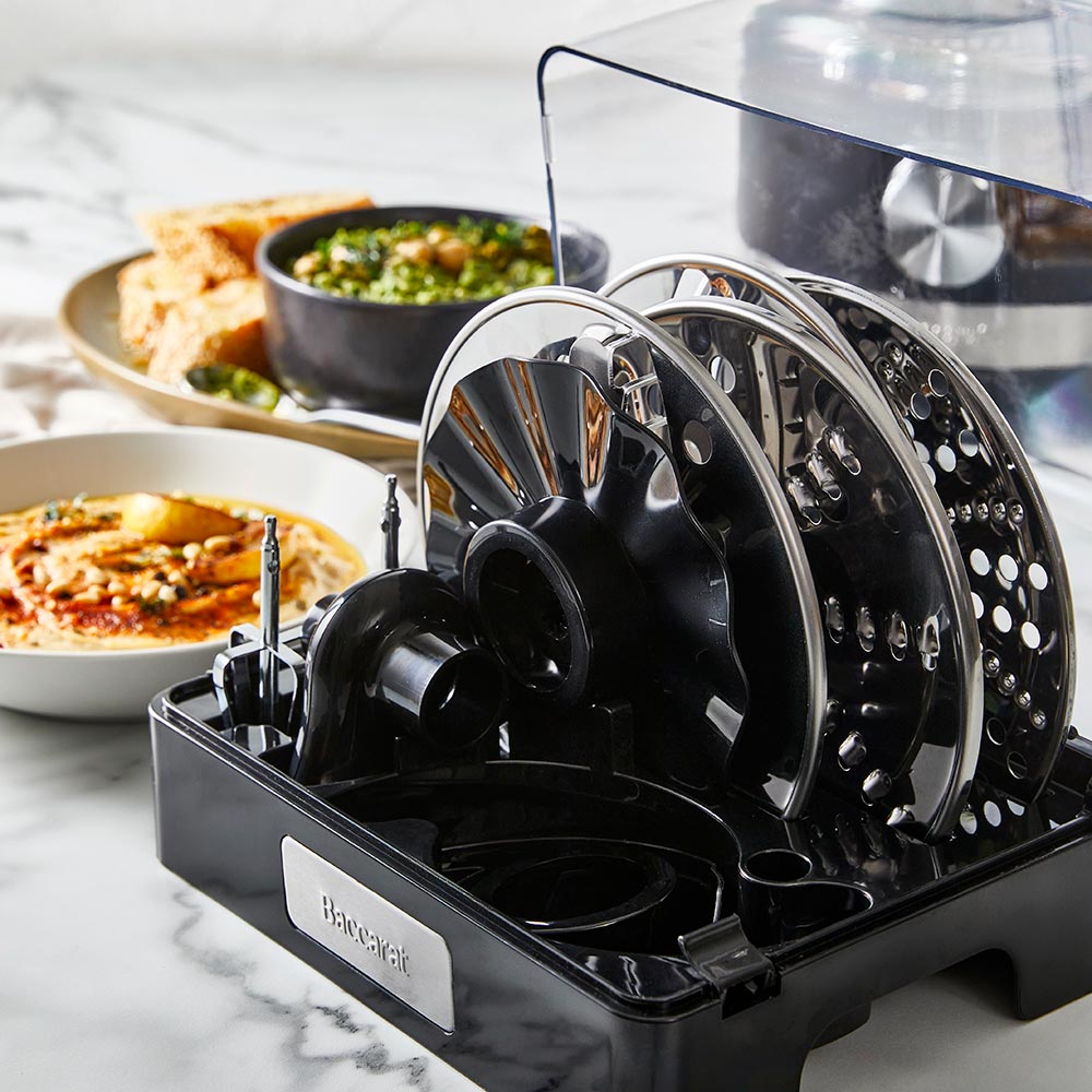 black air fryer with green ingredients on marble counter near dishes and a spice grinder - Baccarat