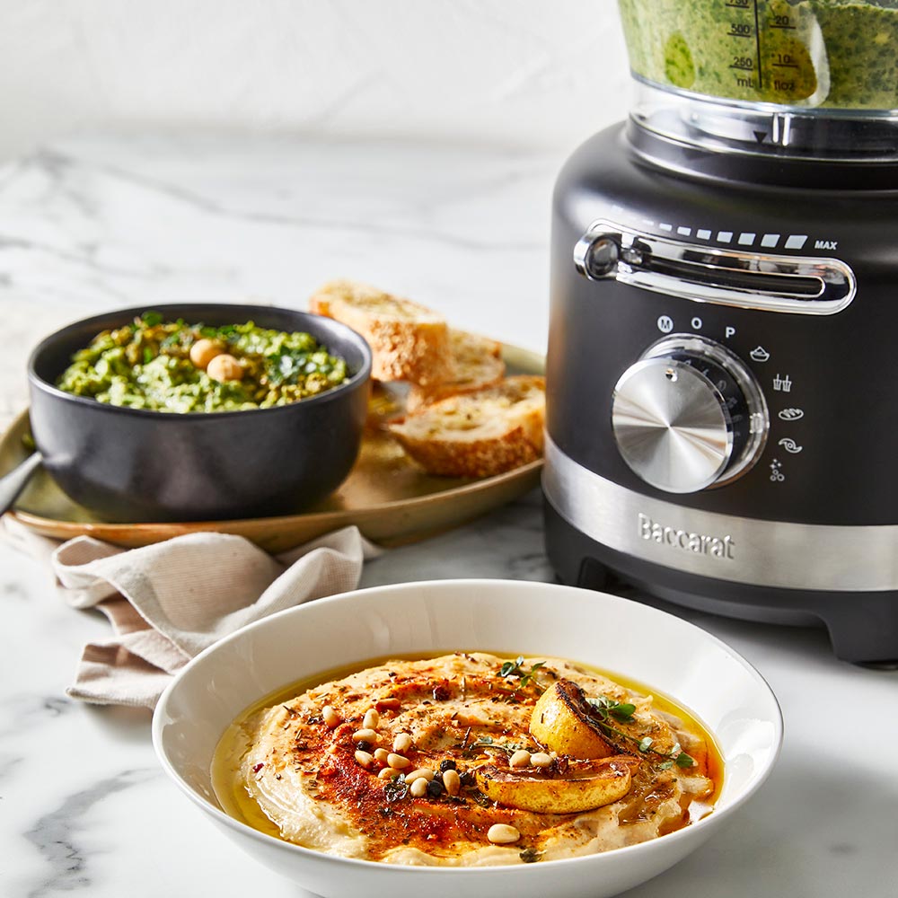 black air fryer with green ingredients on marble counter near dishes and a spice grinder - Baccarat