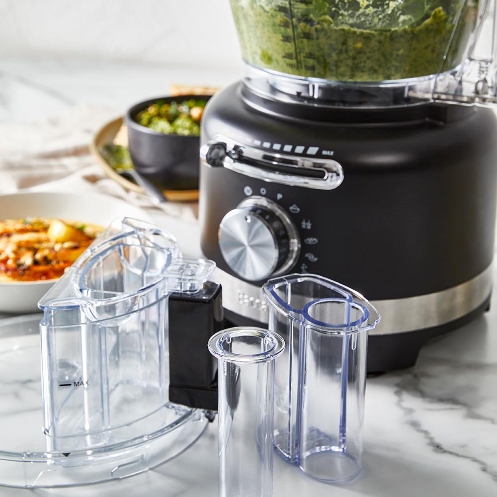 black air fryer with green ingredients on marble counter near dishes and a spice grinder - Baccarat