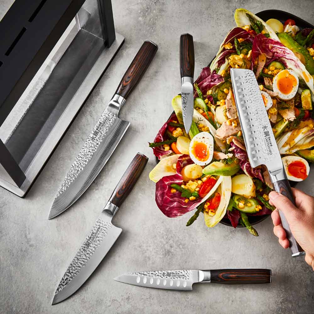 Sharp kitchen knives surround a colourful salad with eggs on a gray surface - Damashiro Emperor Hisa
