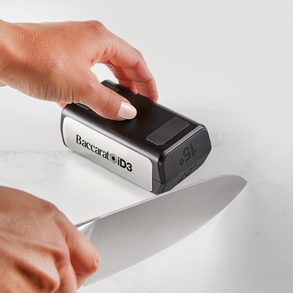 Hand sharpening a large kitchen knife on a gray sharpening stone gray knife sharpener - Baccarat