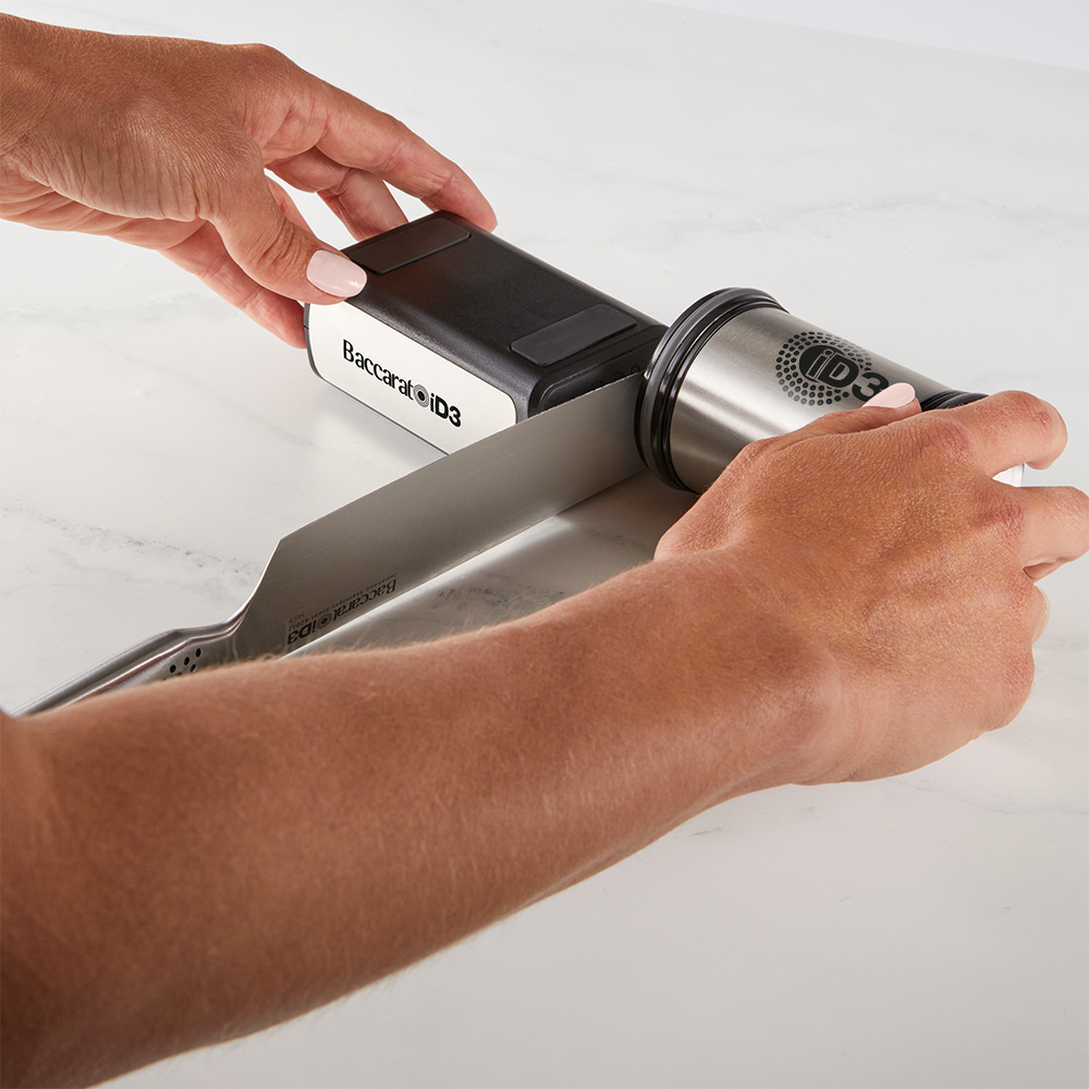 Hand sharpening a large kitchen knife on a gray sharpening stone gray knife sharpener - Baccarat