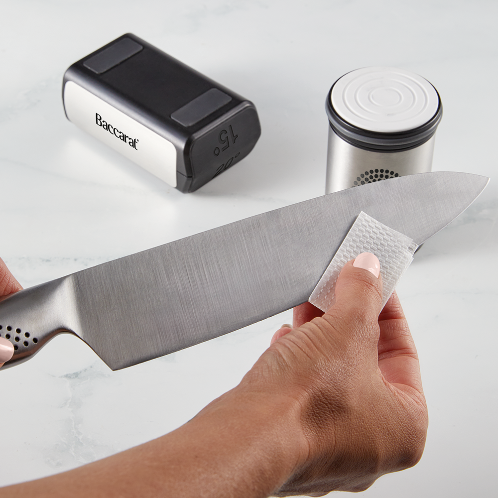 Hand sharpening a large kitchen knife on a gray sharpening stone gray knife sharpener - Baccarat