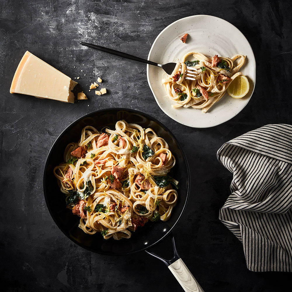 Creamy pasta with herbs on a white plate with parmesan wedge and non stick frypan 20cm - Baccarat