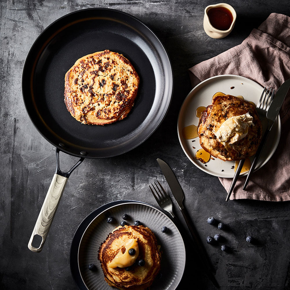 Pancakes in skillet next to syrup topped pancakes on plate non stick frypan 24cm - Baccarat