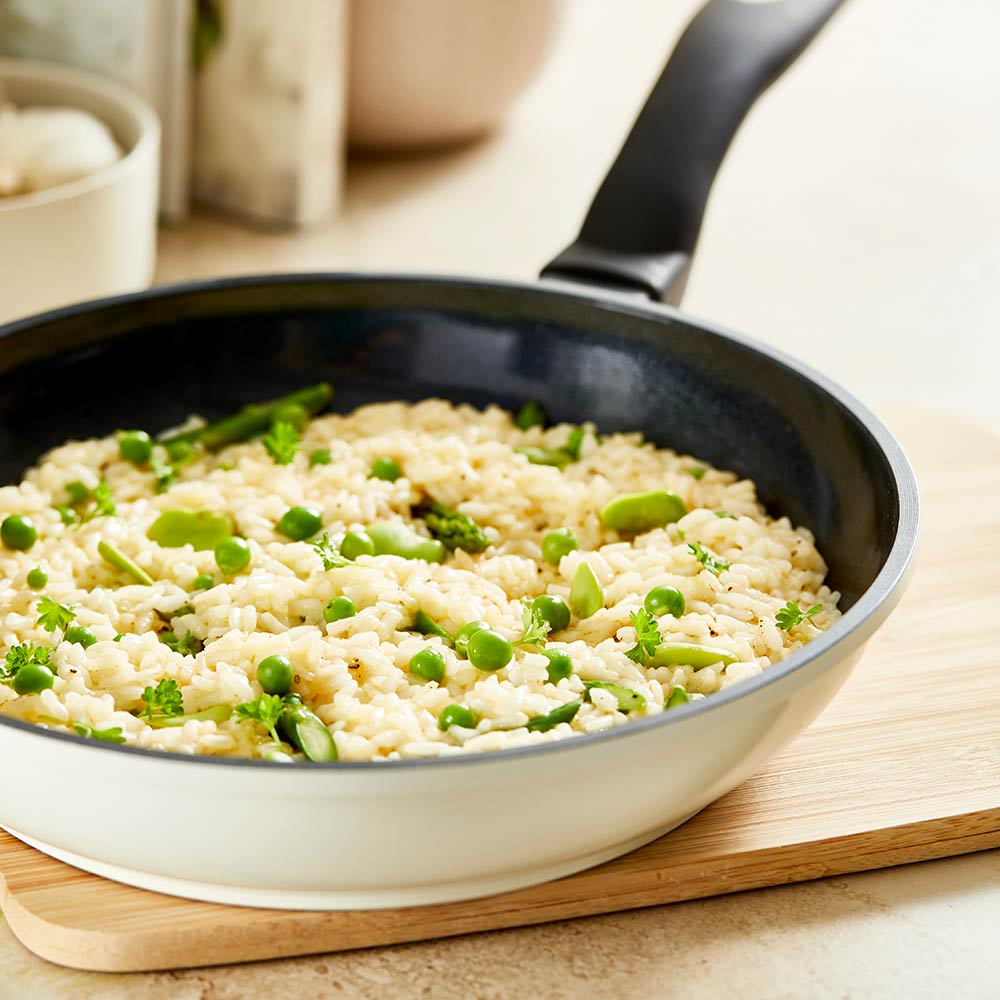 A creamy risotto with green peas in a white pan on a wooden board - cream bio frypan 20cm - Baccarat