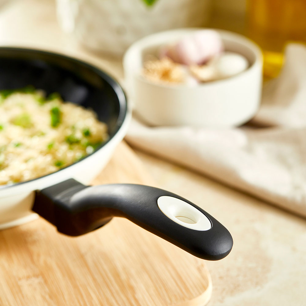 A creamy risotto with green peas in a white pan on a wooden board - cream bio frypan 20cm - Baccarat