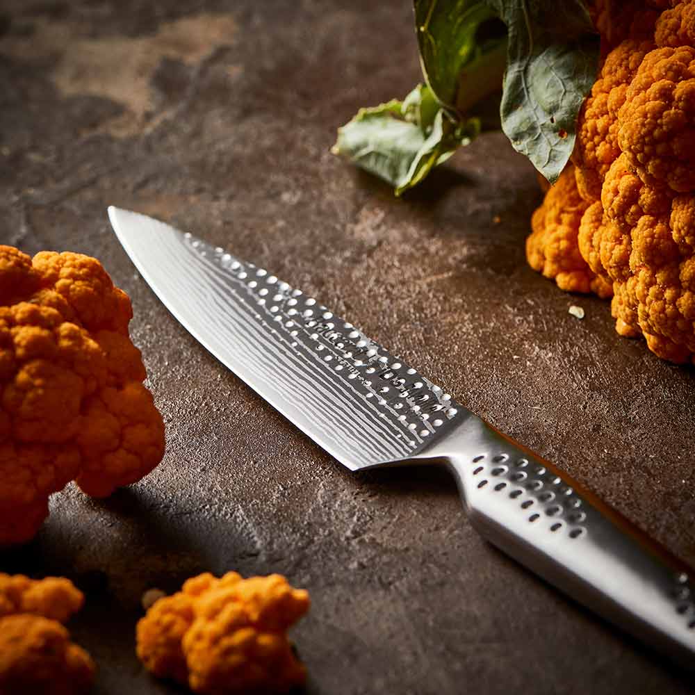 Close-up of a silver utility knife on a wooden surface and orange cauliflower - Baccarat id3 Samurai
