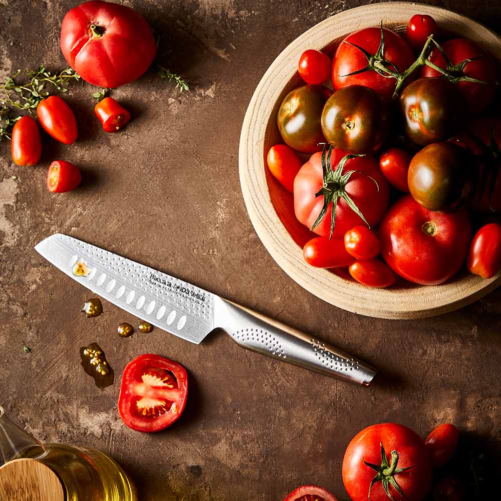 Fresh tomatoes in a wooden bowl with a silver knife on a brown surface - 11cm knife Samurai Santoku