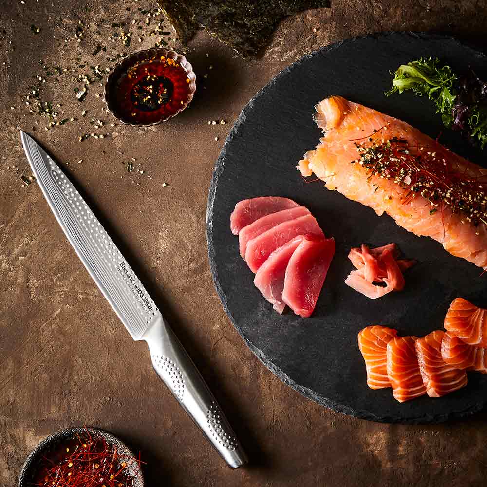 A sharp knife rests beside sliced raw fish on a slate board silver kitchen knife 20cm - Baccarat