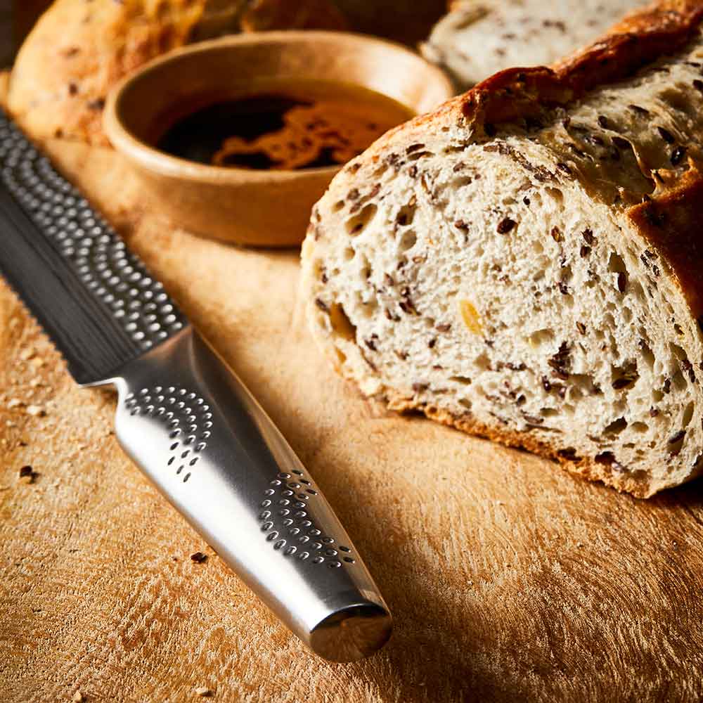 Close-up of serrated knife with sliced multigrain bread on wooden board silver knife 20cm - Baccarat
