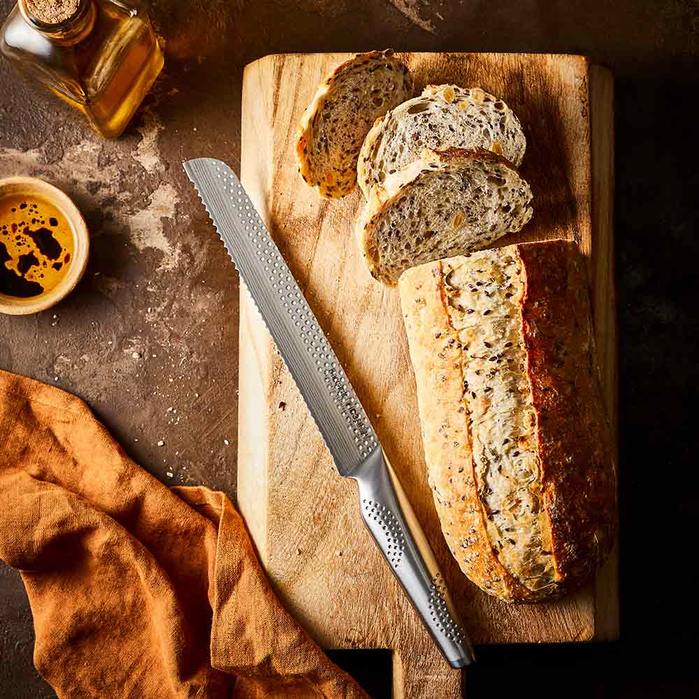 Close-up of serrated knife with sliced multigrain bread on wooden board silver knife 20cm - Baccarat
