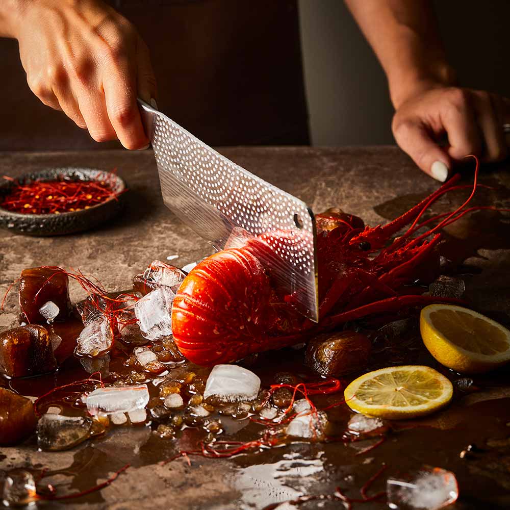 Steel knife with intricate patterns next to a red lobster on ice Samurai bread knife 20cm - Baccarat
