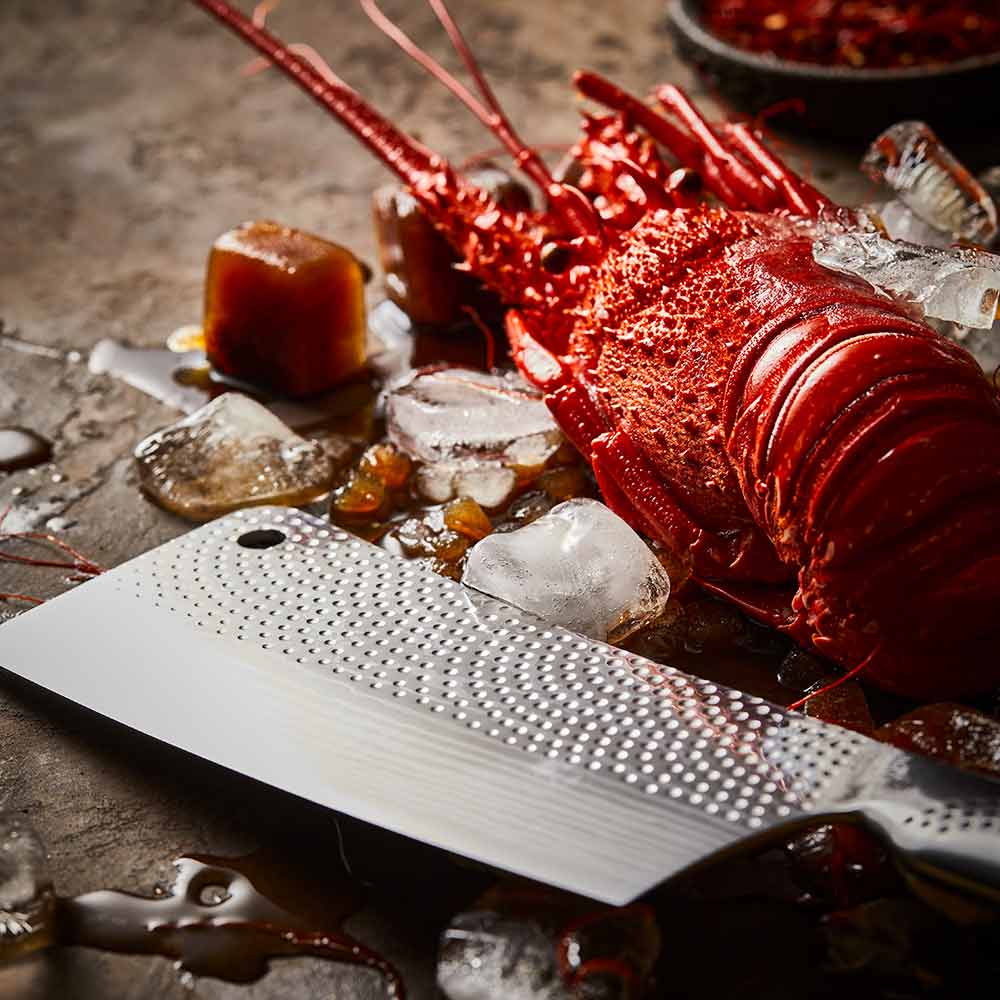 Steel knife with intricate patterns next to a red lobster on ice Samurai bread knife 20cm - Baccarat