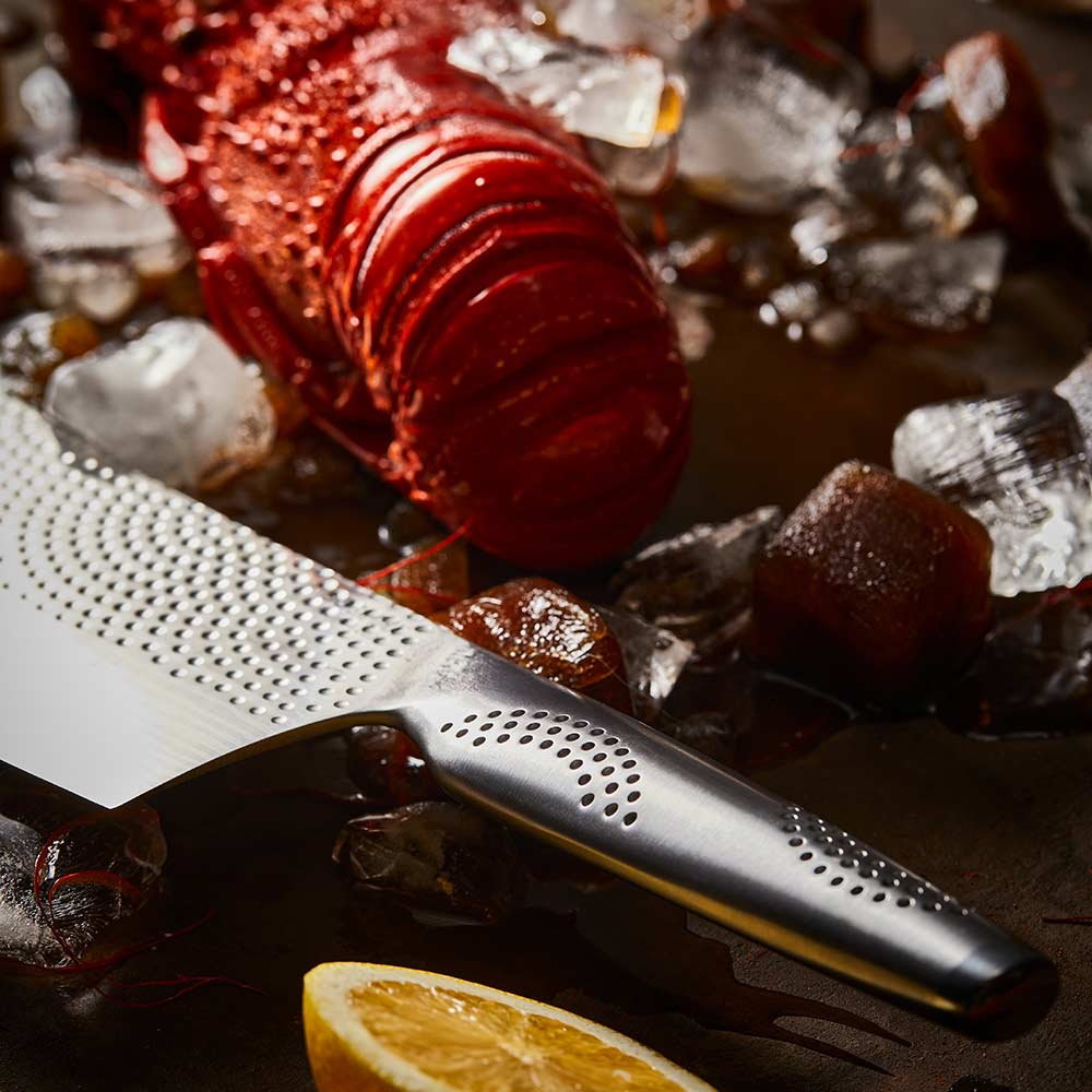 Steel knife with intricate patterns next to a red lobster on ice Samurai bread knife 20cm - Baccarat