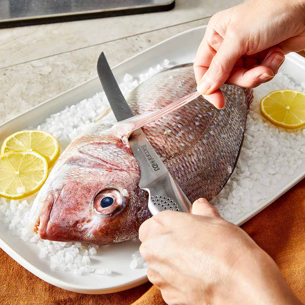 A close-up of a silver stainless steel knife on a wooden cutting board stainless steel knife - Kachi