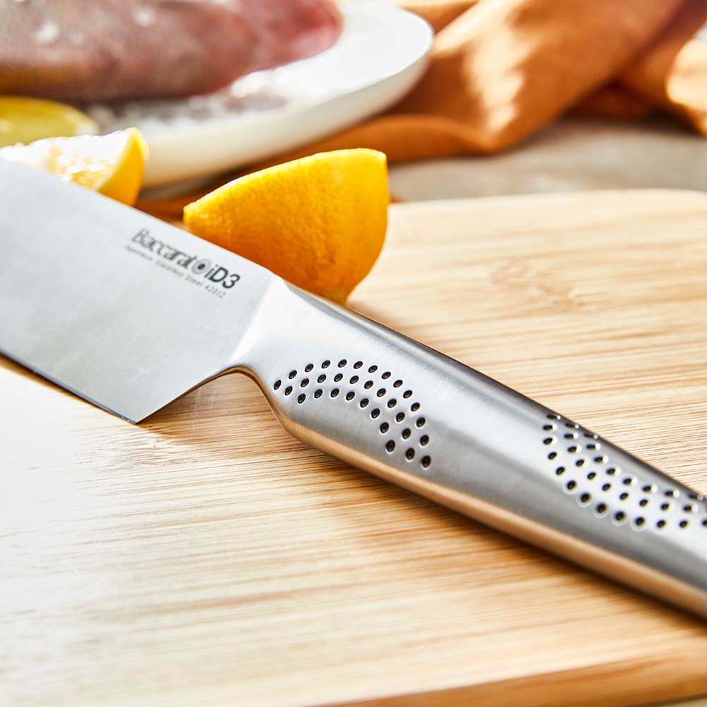 A close-up of a silver stainless steel knife on a wooden cutting board stainless steel knife - Kachi