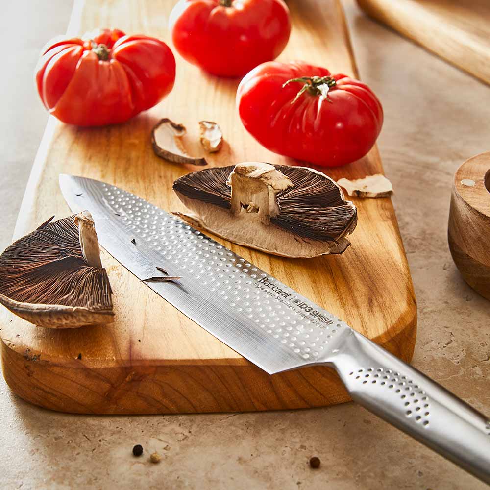 A set of fourteen sleek silver kitchen knives neatly arranged stainless steel knife block - Baccarat