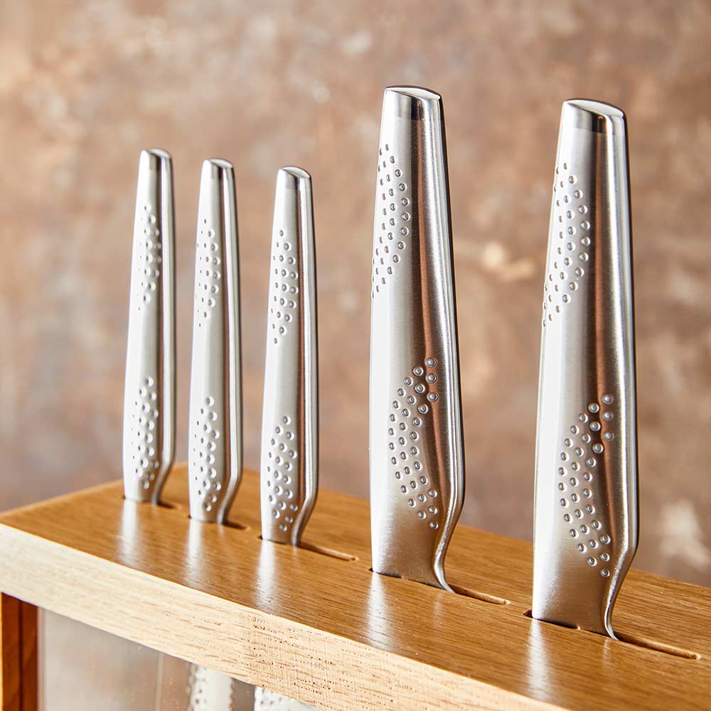 A set of fourteen sleek silver kitchen knives neatly arranged stainless steel knife block - Baccarat