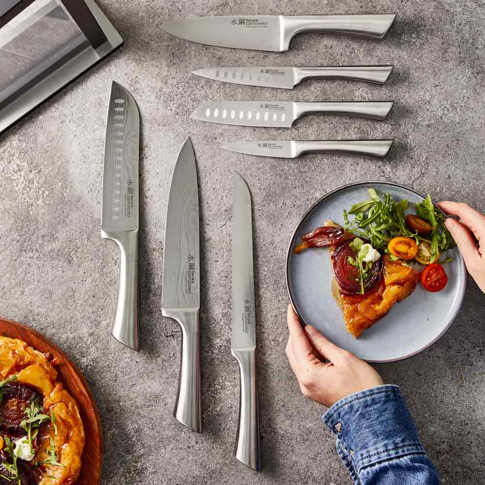 Close-up of Baccarat Damashiro Satori kitchen knife with a patterned blade on a grey countertop