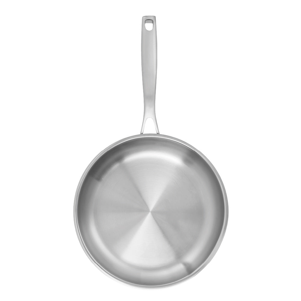 Person flips chicken with a black spatula in a stainless steel frying pan on wooden board - Baccarat