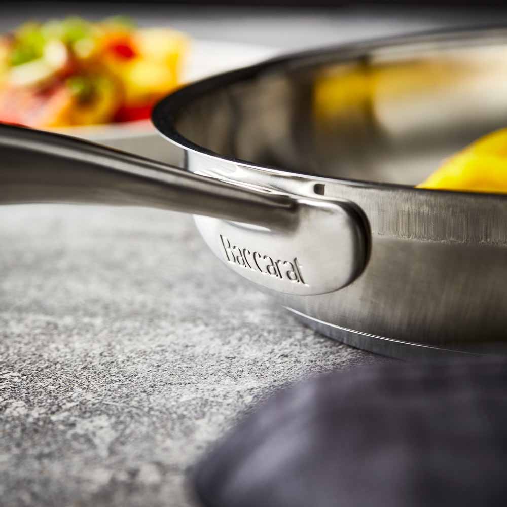 Five stainless steel cookware pieces with vegetables on a kitchen counter 24cm stockpot - Baccarat